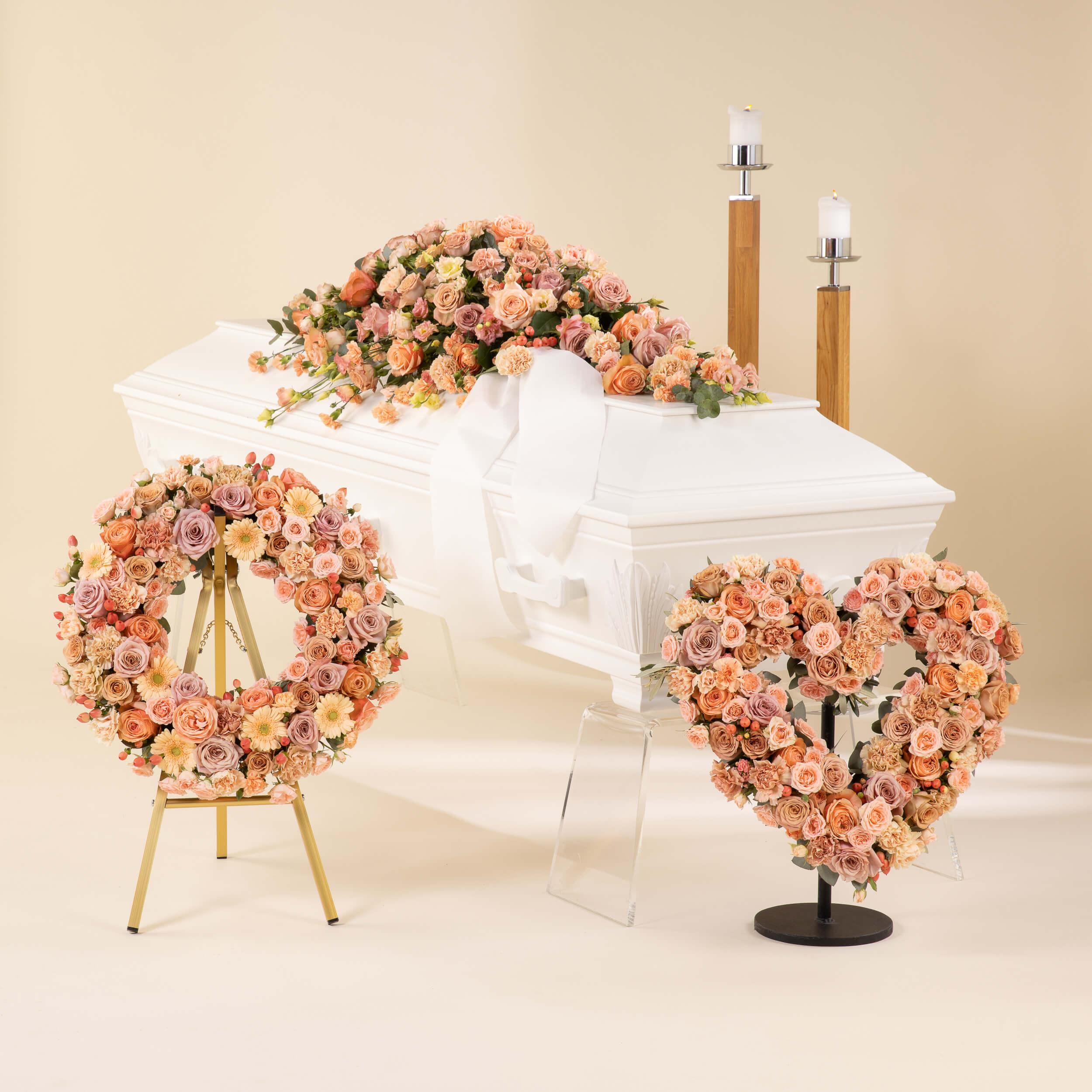 Blomster til begravelse med kistedekorasjon, krans og hjerteformet begravelseskrans i duse fargede blomster.